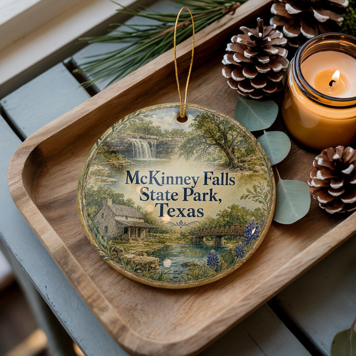 A wooden tray with a decorative ornament featuring a scenic image of McKinney Falls State Park, Texas, and pine cones.
