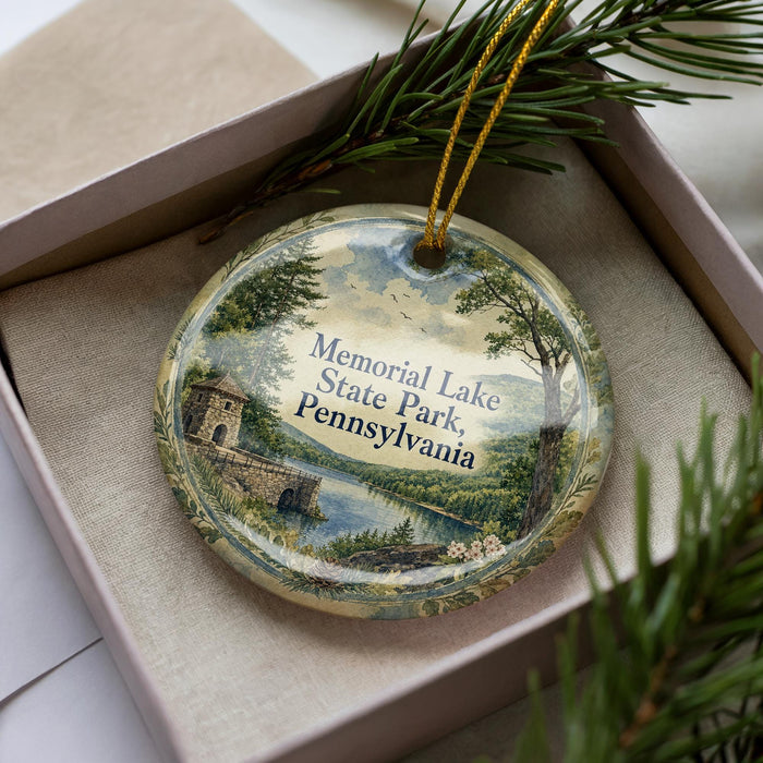 A decorative ornament in a box, featuring a scenic landscape with a lake, mountains, and a castle.