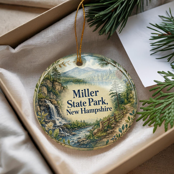 A decorative ornament with a scenic landscape of Miller State Park, New Hampshire, featuring a waterfall and pine trees.