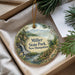 A decorative ornament with a scenic landscape of Miller State Park, New Hampshire, featuring a waterfall and pine trees.