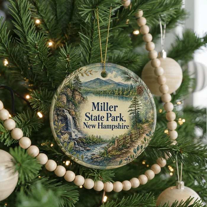 A round ornament hanging on a Christmas tree, featuring a scenic landscape with a waterfall and mountains.