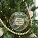 A round ornament hanging on a Christmas tree, featuring a scenic landscape with a waterfall and mountains.