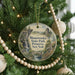 A round ornament hanging on a Christmas tree, featuring a scenic landscape with a castle, trees, and a waterfall.
