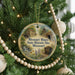 A round ornament hanging on a Christmas tree, featuring a scenic image of the Missouri Mines State Historic Site in Missouri.