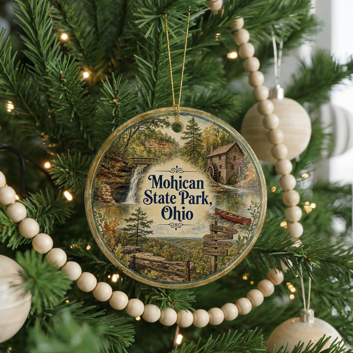 A circular ornament hanging on a Christmas tree, featuring a scenic image of Mohican State Park, Ohio.