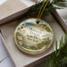 A decorative ornament in a box, featuring a lighthouse and a scenic landscape, with the text "Montauk Downs State Park, New York" prominently displayed.