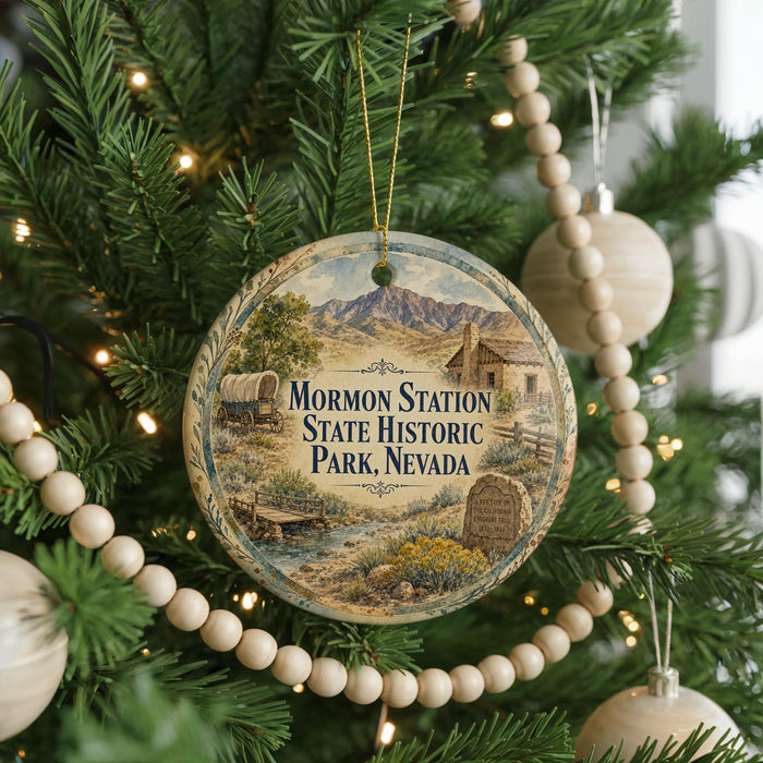 A round ornament hanging on a Christmas tree, featuring a scenic landscape with mountains and a wagon, along with the text "M Mormon Station State Historic Park, Nevada".