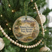A round ornament hanging on a Christmas tree, featuring a scenic landscape with mountains and a wagon, along with the text "M Mormon Station State Historic Park, Nevada".