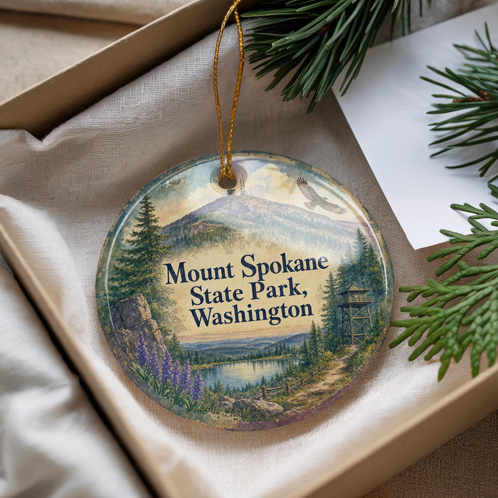 A decorative ornament with a scenic landscape of Mount Spokane State Park, Washington, featuring a mountain, pine trees, and a lake.