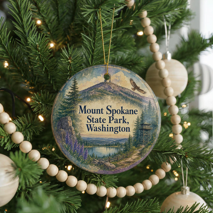 A Christmas tree decorated with ornaments, including a circular ornament with a scenic mountain landscape and text that reads "Mount Spokane State Park, Washington".