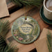 A decorative ornament featuring a scenic image of the Natural Bridge in Virginia, surrounded by pine branches and a cup of coffee on a wooden surface.