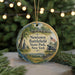 A round ornament with a painting of a cannon, trees, and a monument, hanging on a string.