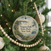 A round ornament hanging on a Christmas tree, featuring a scenic image of Niagara Falls State Park in New York.