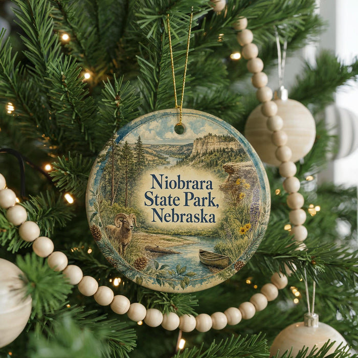 A round ornament hanging on a Christmas tree, featuring a scenic landscape of Niobrara State Park, Nebraska.