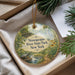 A decorative ornament with a scenic image of a river and park, featuring a bird and a bridge, is displayed in a box with pine branches.
