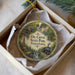 A decorative ornament in a box, featuring illustrations of a train, a waterfall, and a cabin, with the text "OIL CREEK STATE PARK, PENNSYLVANIA" printed on it.