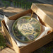 A decorative ornament in a wooden box, featuring illustrations of Pennsylvania State Park and the Pennsylvania oil field.