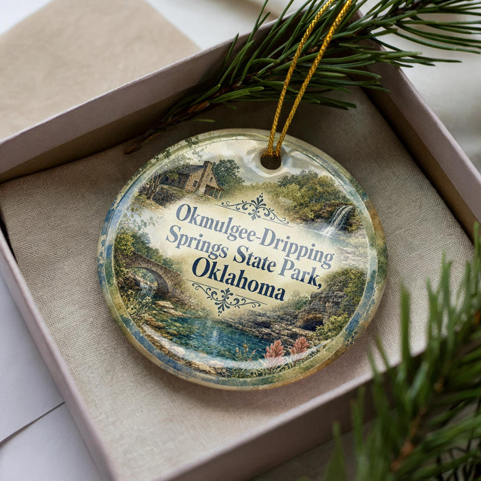 A decorative ornament with a scenic image of Okmulgee Springs State Park, Oklahoma, displayed in a box with pine branches.