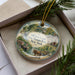 A decorative ornament in a box, featuring a scenic image of the Old Erie Canal and historic park in New York.