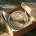 A circular ornament with the text "PARC NATIONAL ECRIANS FRANCE" is displayed in a wooden box, surrounded by greenery.