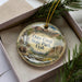 A decorative ornament in a box, featuring an illustration of Otter Creek State Park in Utah.