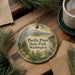 A decorative ornament with the text "Pacific Pines State Park, Washington" is displayed on a wooden surface, surrounded by pine branches and a cup of coffee.