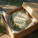 A decorative ornament in a wooden box, featuring a scenic image of Pacific Pines State Park in Washington.