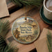 A decorative ornament featuring a cowboy on horseback, with the text "Pancho Villa State Park, New Mexico" displayed on it. The ornament is placed on a wooden surface, surrounded by pine branches and a cup of coffee.