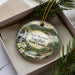 A decorative ornament featuring a scenic landscape of Paris Mountain State Park, South Carolina, with a waterfall and pine trees.