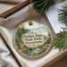 A decorative ornament with a scenic image of the park, featuring a house, a waterfall, and a forest, is displayed in a box with pine branches.