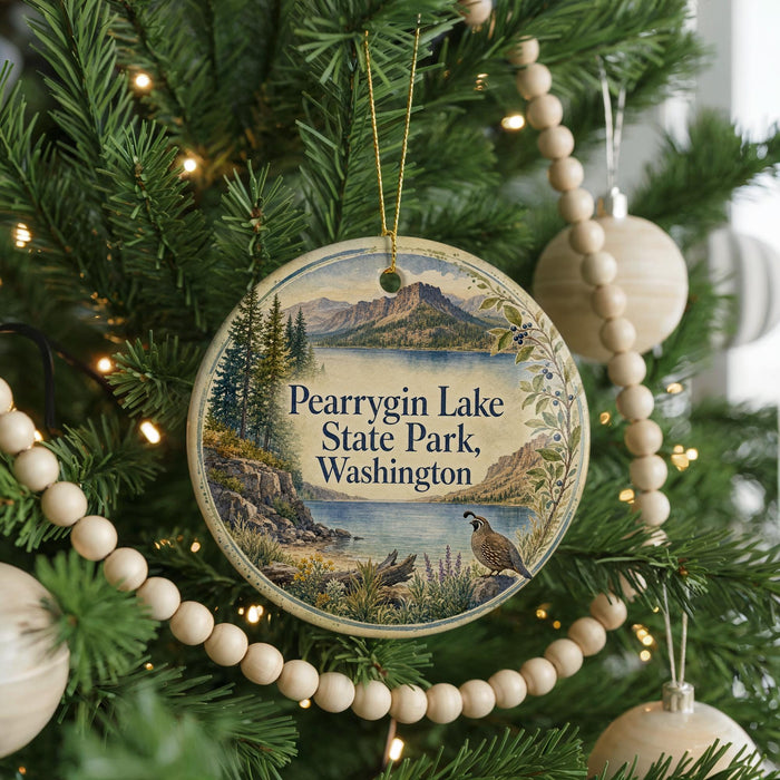 A round ornament hanging on a Christmas tree, featuring a scenic landscape with mountains, trees, and a bird.
