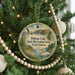 A round ornament hanging on a Christmas tree, featuring a seagull and a lake landscape.