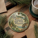 A round ornament with a scenic landscape of Peninsula State Park, Wisconsin, featuring a lighthouse, pine trees, and a body of water.