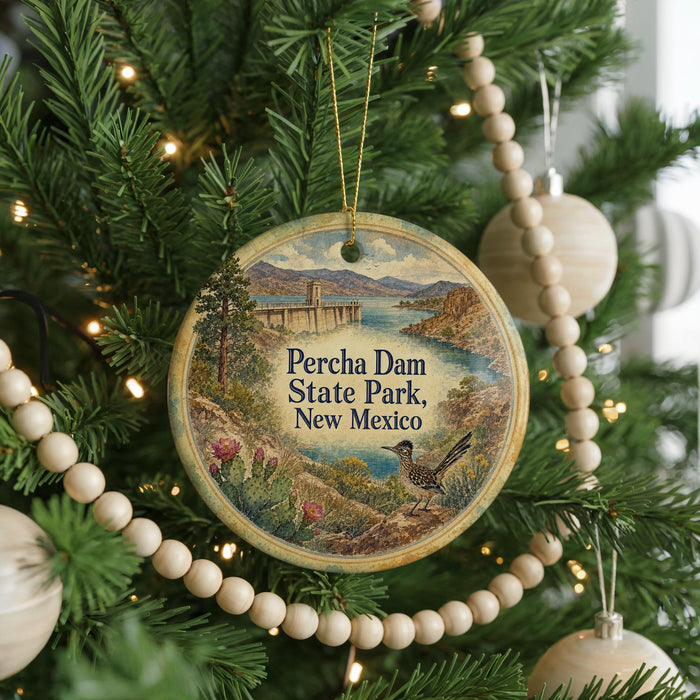 A round ornament hanging on a Christmas tree, featuring a scenic image of Percha Dam State Park, New Mexico.