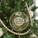 A round ornament hanging on a Christmas tree, featuring a scenic landscape with a waterfall and a castle.