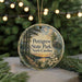 A circular ornament with a scenic image of a park, featuring a wooden walkway, trees, and a sunset, hanging from a string.