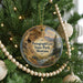 A Christmas tree decorated with ornaments, including a circular ornament with a scenic image of Pictograph Cave in Montana.