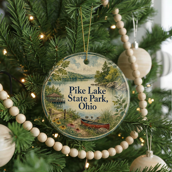 A round ornament hanging on a Christmas tree, featuring a scenic landscape with a lake, trees, and a boat.