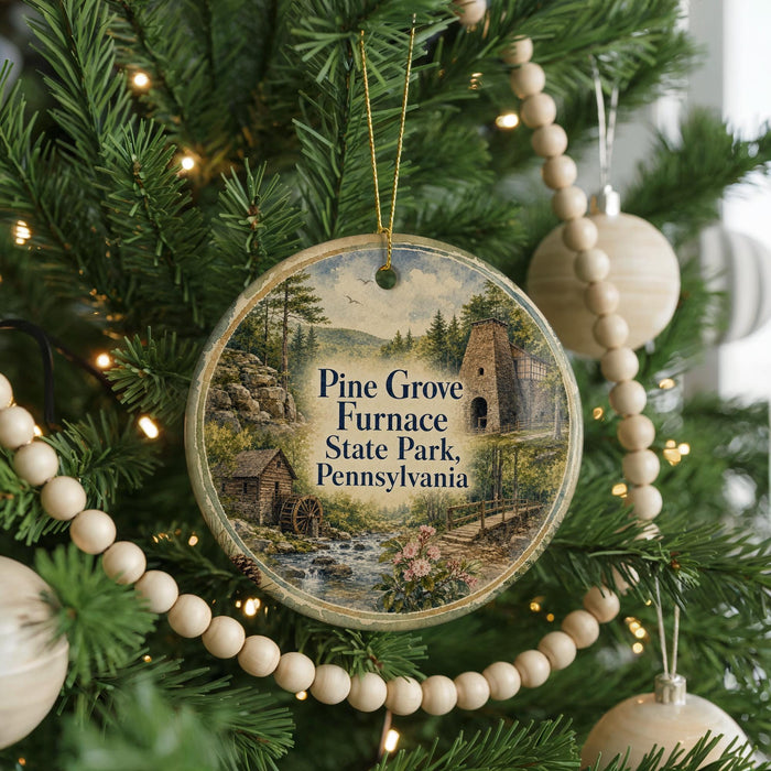 A round ornament hanging on a Christmas tree, featuring a scenic image of Pine Grove Furnace State Park, Pennsylvania.