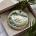 A decorative ornament with a scenic landscape of Pirogue Island, State Park, Montana, featuring mountains, pine trees, and a lake.