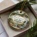 A decorative ornament with a scenic image of Pocahontas State Park, Virginia, displayed in a box with pine branches.