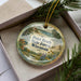 A decorative ornament with a scenic landscape of Point Beach State Forest, Wisconsin, displayed in a box with pine branches.