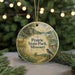 A decorative ornament featuring a scenic landscape of Prairie State Park, Missouri, with a bird perched on a tree branch and a deer in the background.