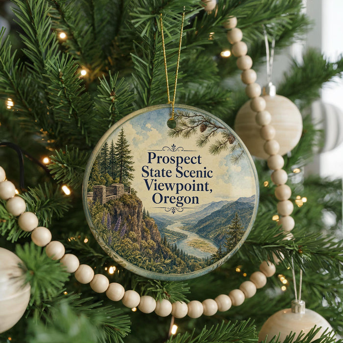 A round ornament hanging on a Christmas tree, featuring a scenic landscape with mountains, trees, and a river.