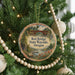 A round ornament hanging on a Christmas tree, featuring a scenic image of the Red Bridge in Oregon.