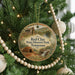 A round ornament hanging on a Christmas tree, featuring a scenic image of Red Clay State Historic Park in Tennessee.