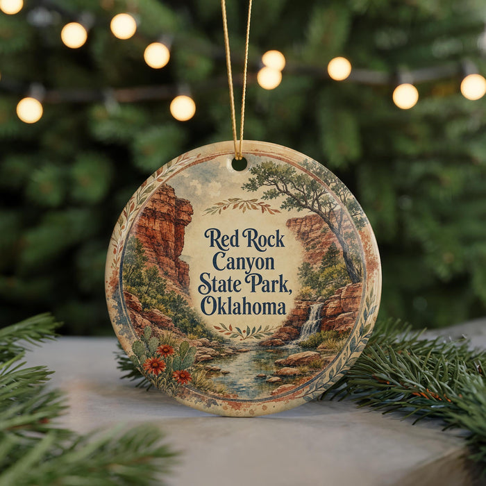 A decorative ornament featuring a scenic landscape with a waterfall and mountains, hanging on a string.
