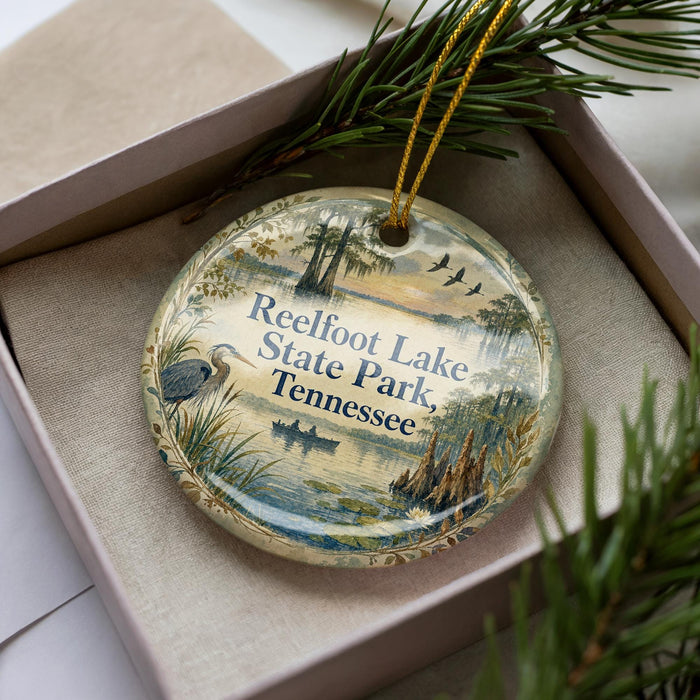 A decorative ornament with a scenic image of Reelfoot Lake State Park in Tennessee, featuring a bird, palm trees, and a body of water.