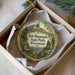 A decorative ornament in a box, featuring a scenic image of Rib Mountain State Park, Wisconsin.