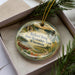 A decorative ornament in a box, featuring a scenic landscape with a lake, mountains, and a canoe, along with the text "Richard Bong State Recreation Area, Wisconsin".